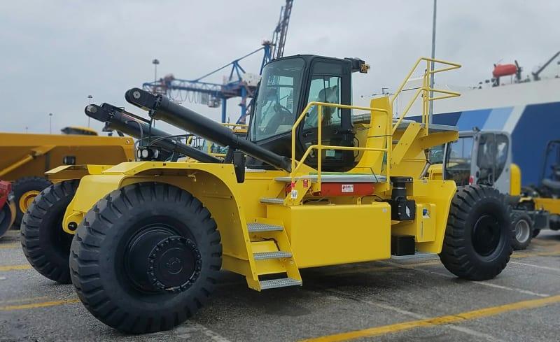 A yellow forklift sits in a parking lot near other construction equipment.