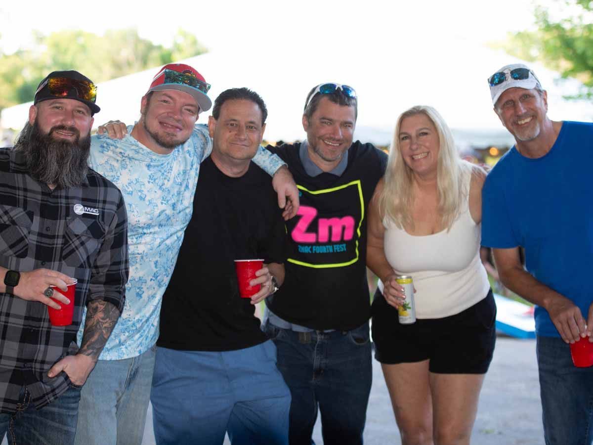 Members of the ZMac team smile together holding drinks at a ZMac outing.