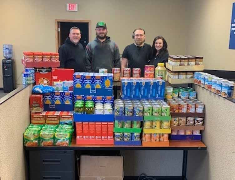 Members of the ZMac team volunteering for charity with boxes of donated food.