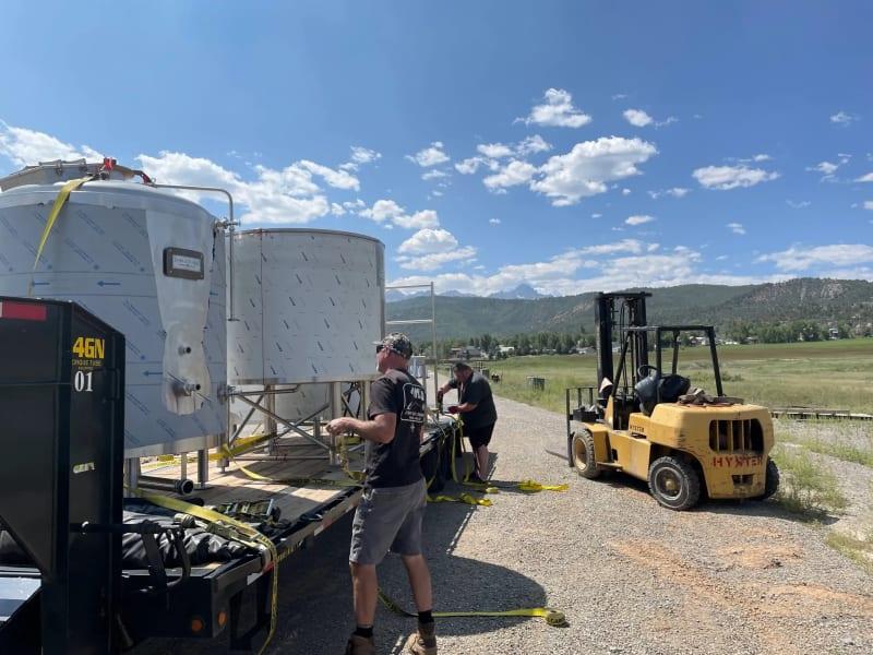 A team straps brewing equipment for a pub to a truck bed.