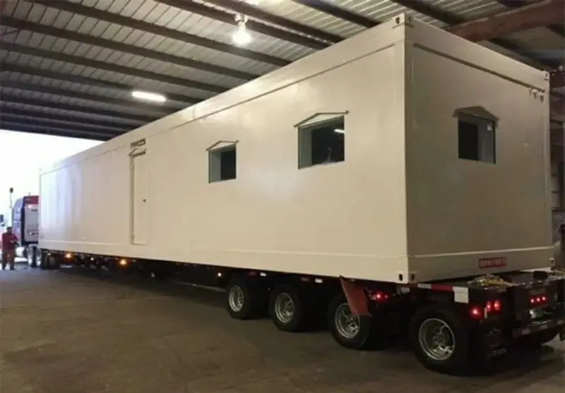 A modular building sits on a truck bed.