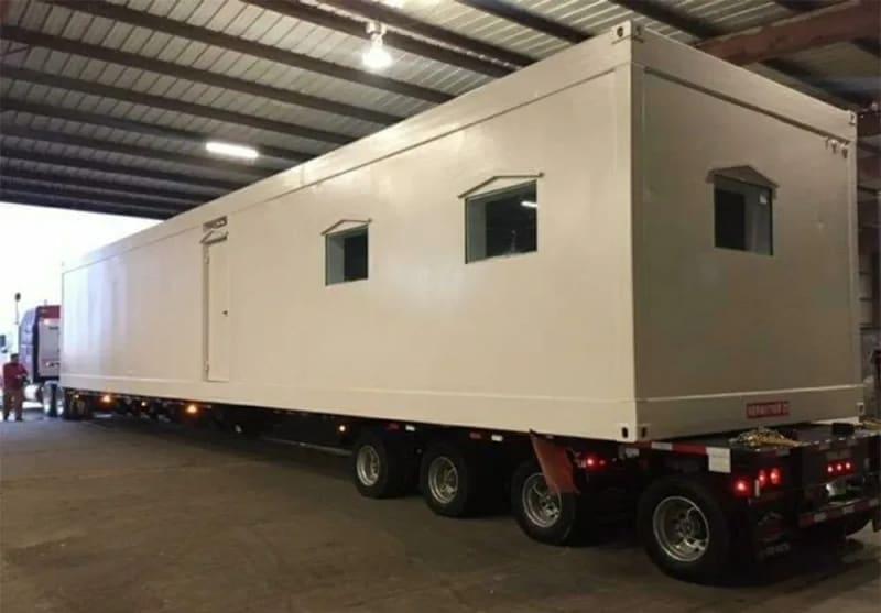 A modular building sits on a truck bed.