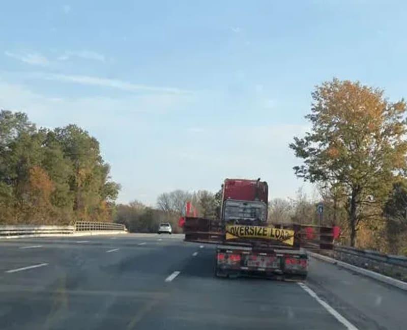 The rear of a truck with an oversized freight banner driving down the road.