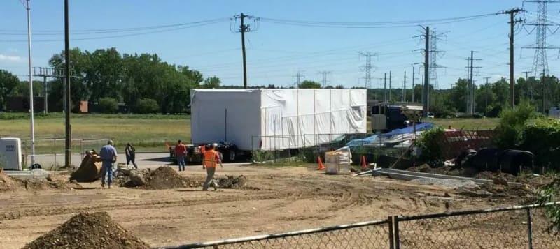 A truck carrying a prefabricated building sits at a job site.
