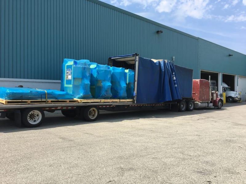 Equipment wrapped in blue packaging sits on the truck bed of a red truck.