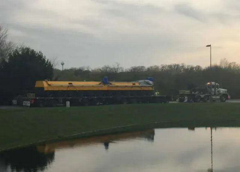 A yellow hydraulic track for a gantry crane attached to a truck bed.