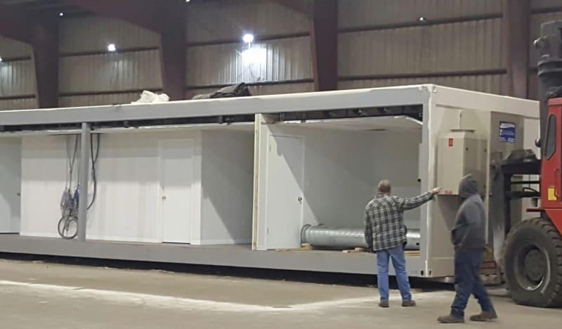 The construction of a blast resistant modular office, with one wall open to show the interior of the space with two rooms