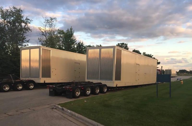 Two generators sit on the truck beds of two trucks.