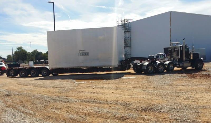 A side angle of a section of a spiral freezer sitting on a truck bed.