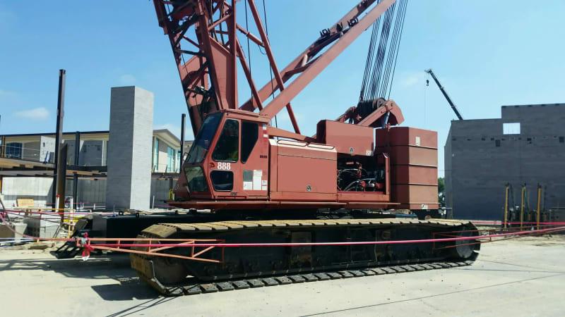 A red construction crane sits in an industrial construction site.