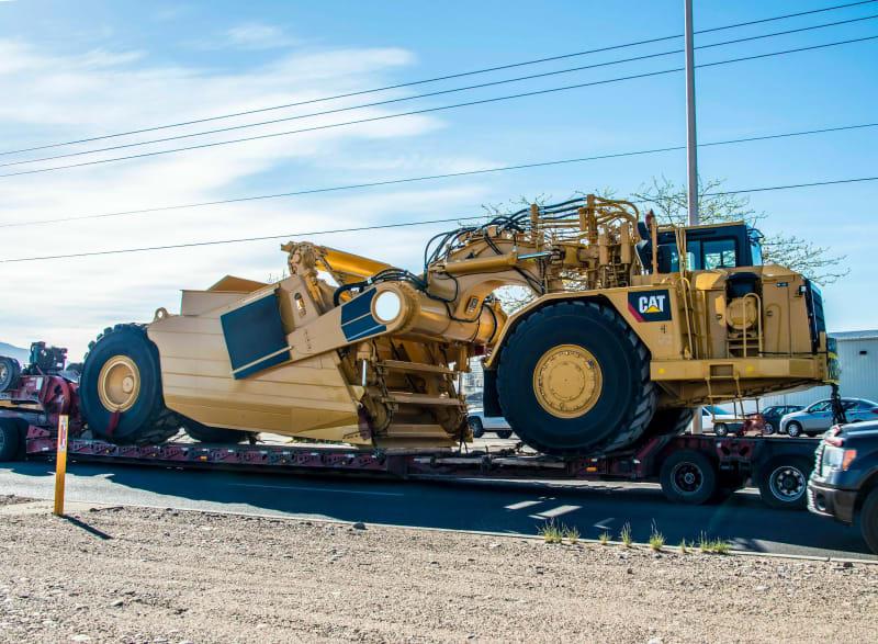 A side view of a yellow construction scraper on a truck
