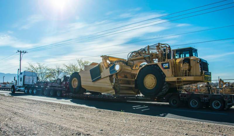 A long angle of a yellow construction scraper on a truck
