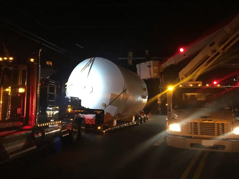 A white fiberglass tank on a truck at night