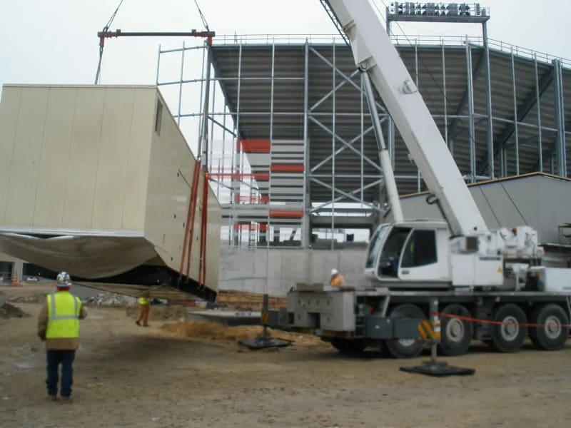 A white crane lifts a generator at a construction site