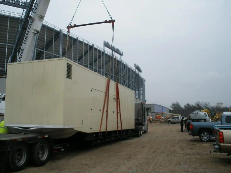A generator on a truck bed with straps attached to a crane