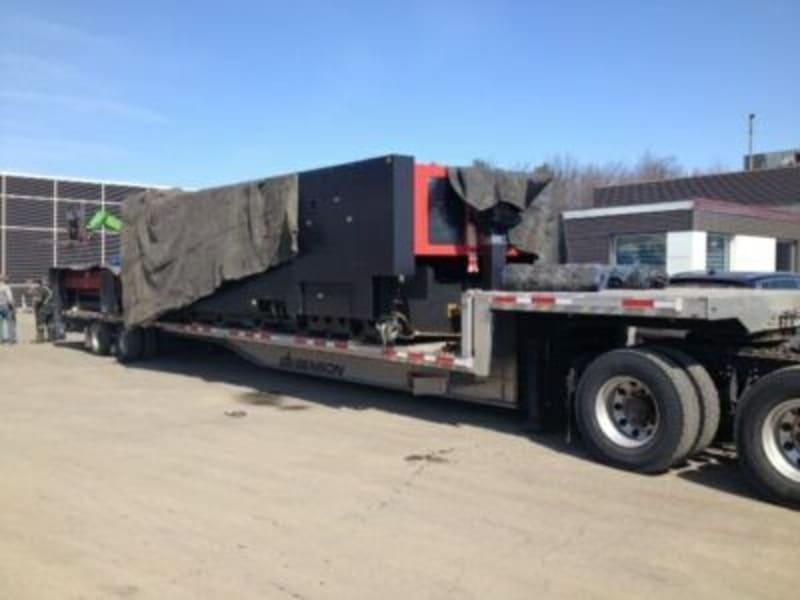 A laser cutter covered in a tarp on a truck bed.