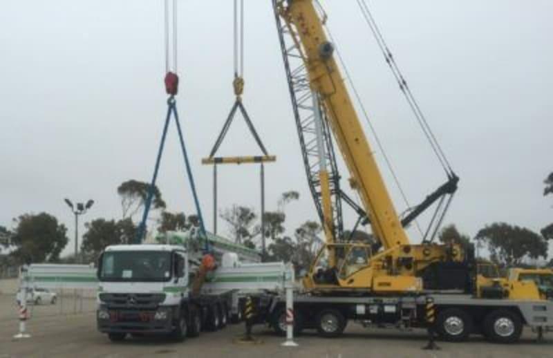 A boom crane being loaded onto a truck.