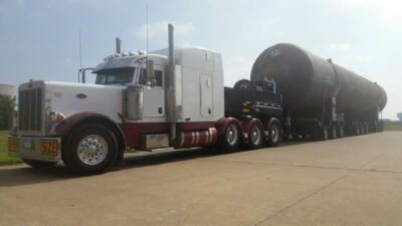 A black steel tank sits on the back of a white truck.