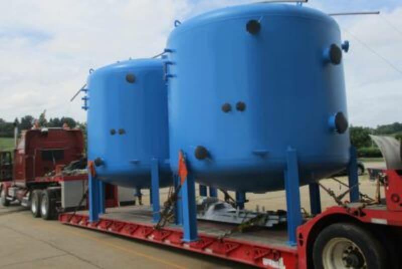 Two large blue tanks sit on a red truck bed.