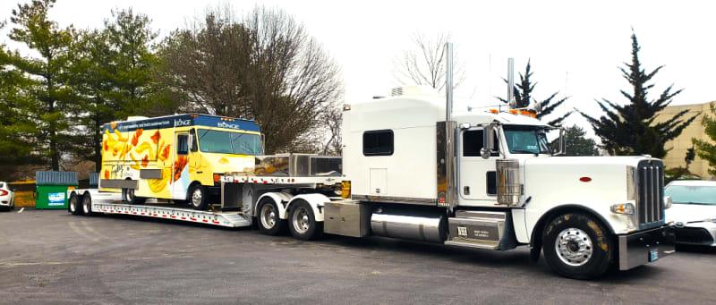 White truck carrying a colorful box truck on the back