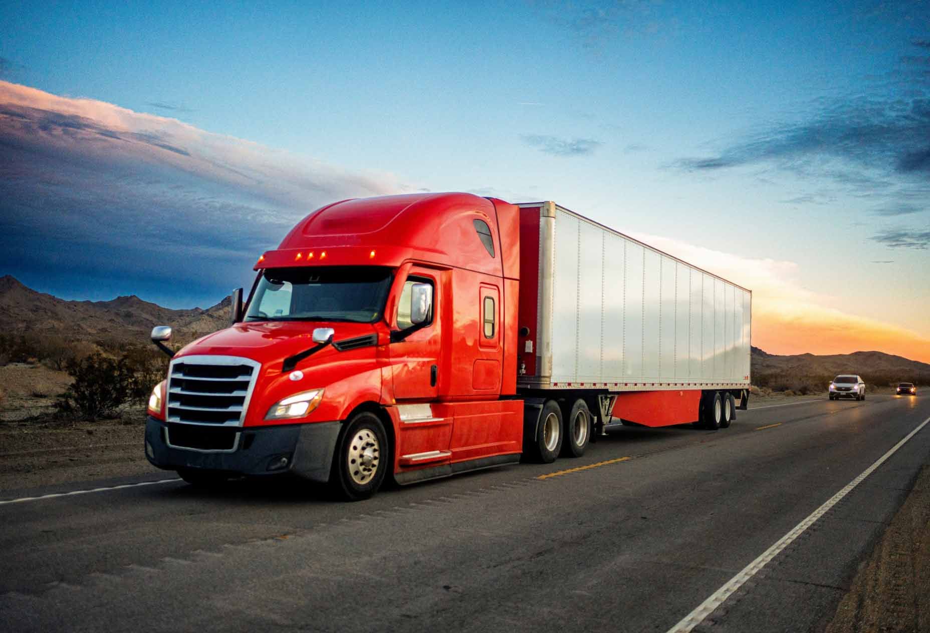 A red enclosed freight truck driving on a highway.