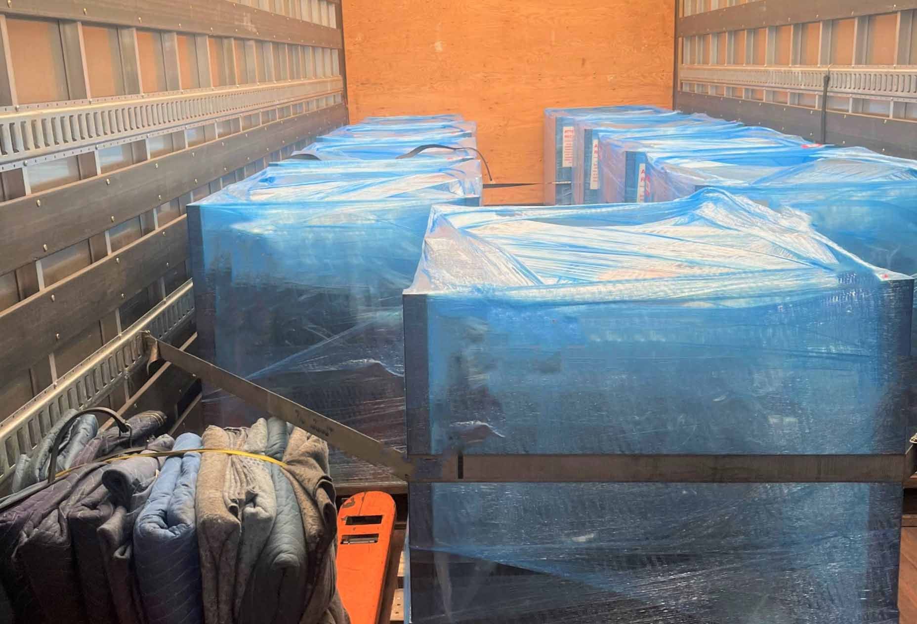 The interior of an enclosed freight truck containing fragile packages and moving blankets.