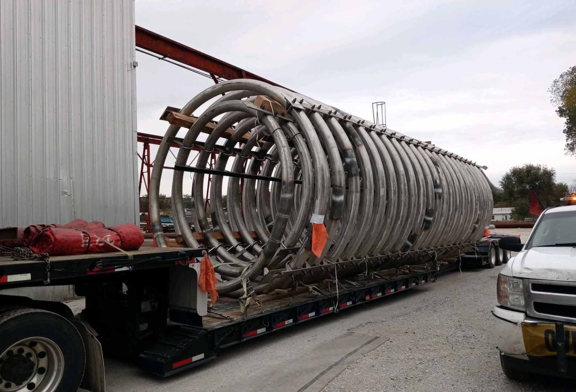 A unique load of a large coiled metal sits on a truck's low bed.