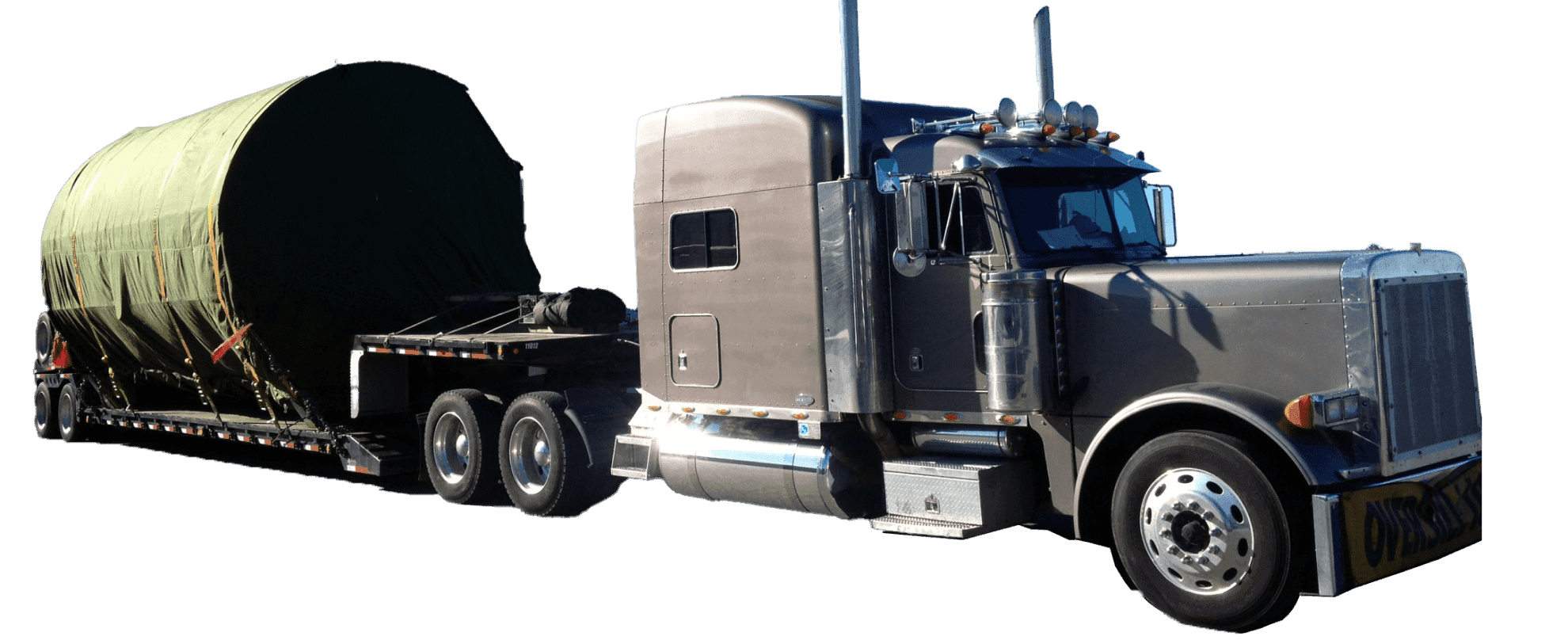 A truck carrying a large, cylindrical load covered in a green tarp.